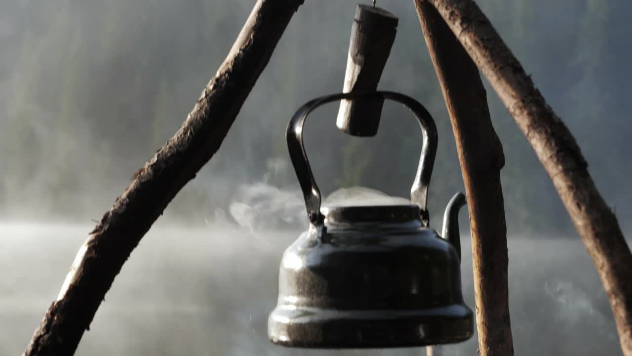 早晨篝火上的古董茶壶。视频素材