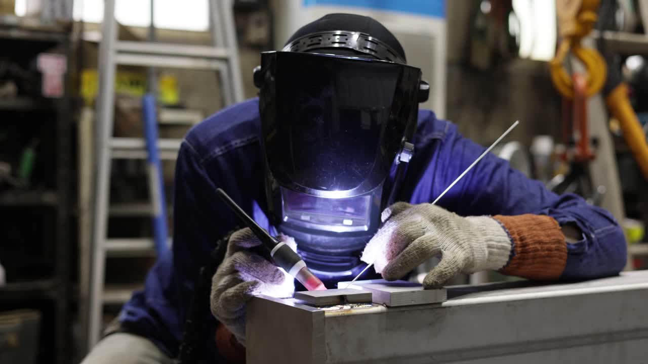 一名成熟的男子在一家小型焊接工厂里焊接视频素材