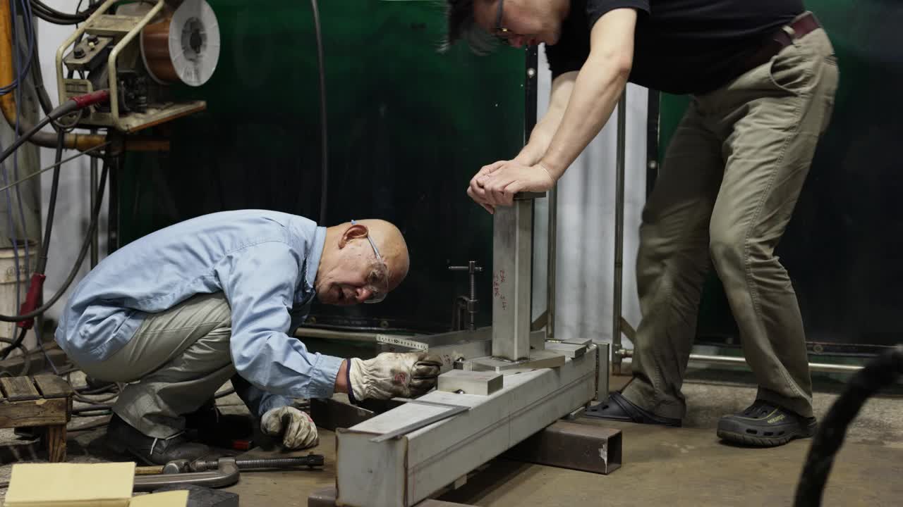 父子俩在一家小型焊接工厂工作视频素材