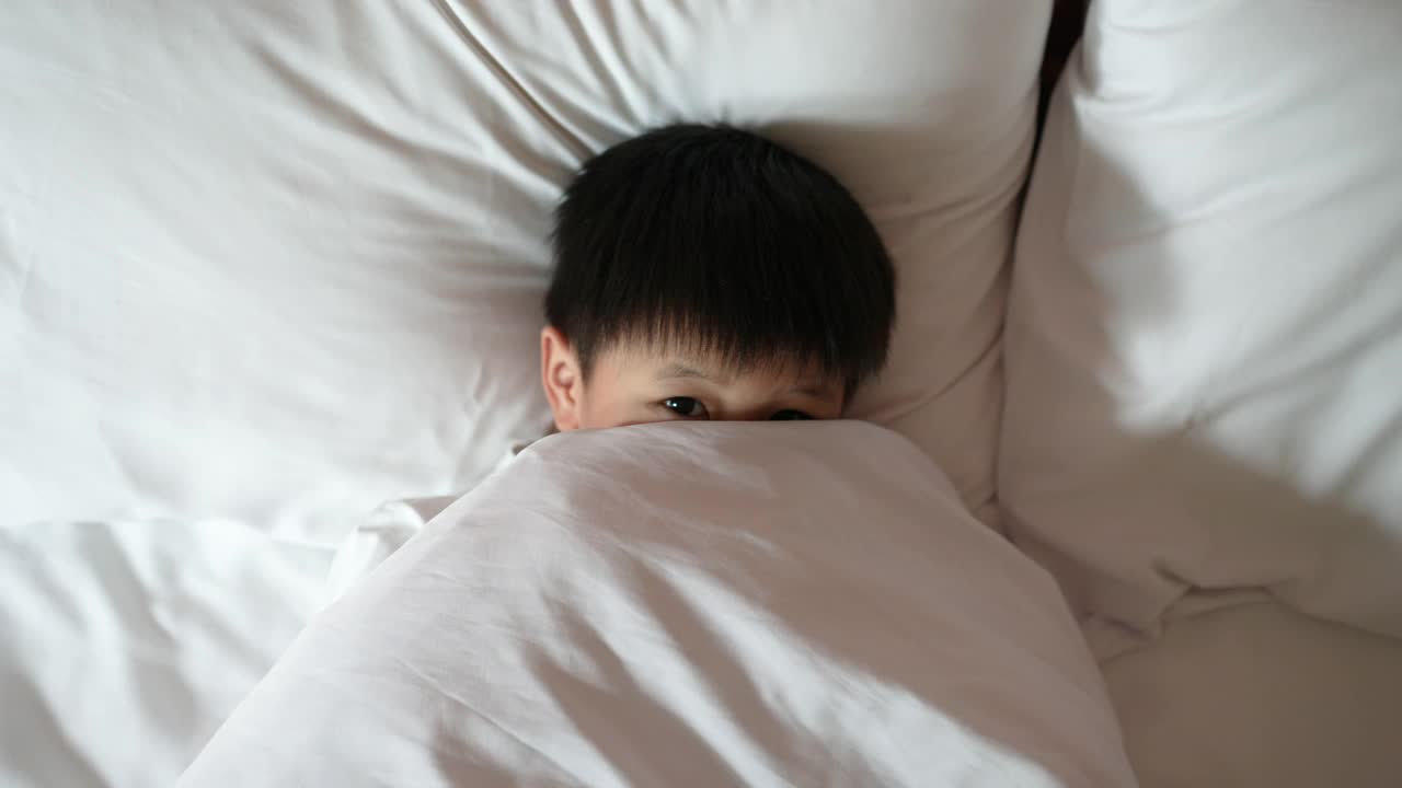 亚洲男孩在卧室里醒来玩躲猫猫视频素材