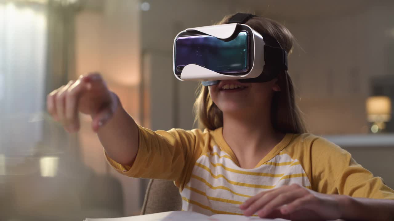 一个小女孩戴着虚拟现实头盔坐在家里的4k视频片段视频素材