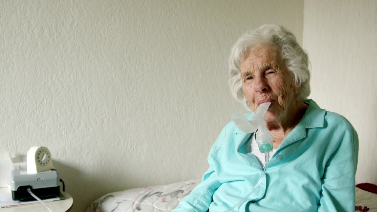 老年白人妇女在使用喷雾器吸入药物治疗哮喘或打开肺部气道时竖起大拇指视频下载