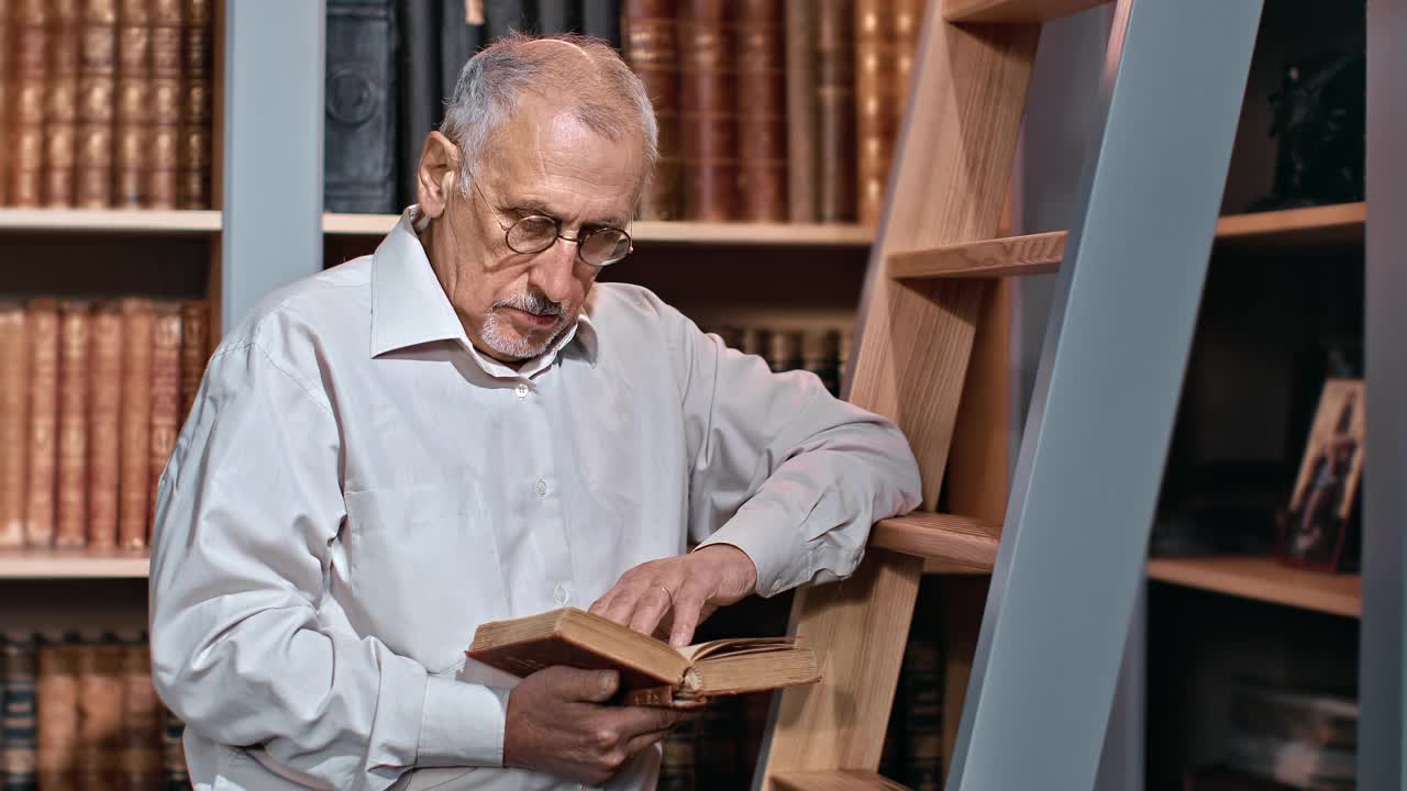 70多岁的男性大学教授在公共图书馆阅读图书检索信息讲座视频素材