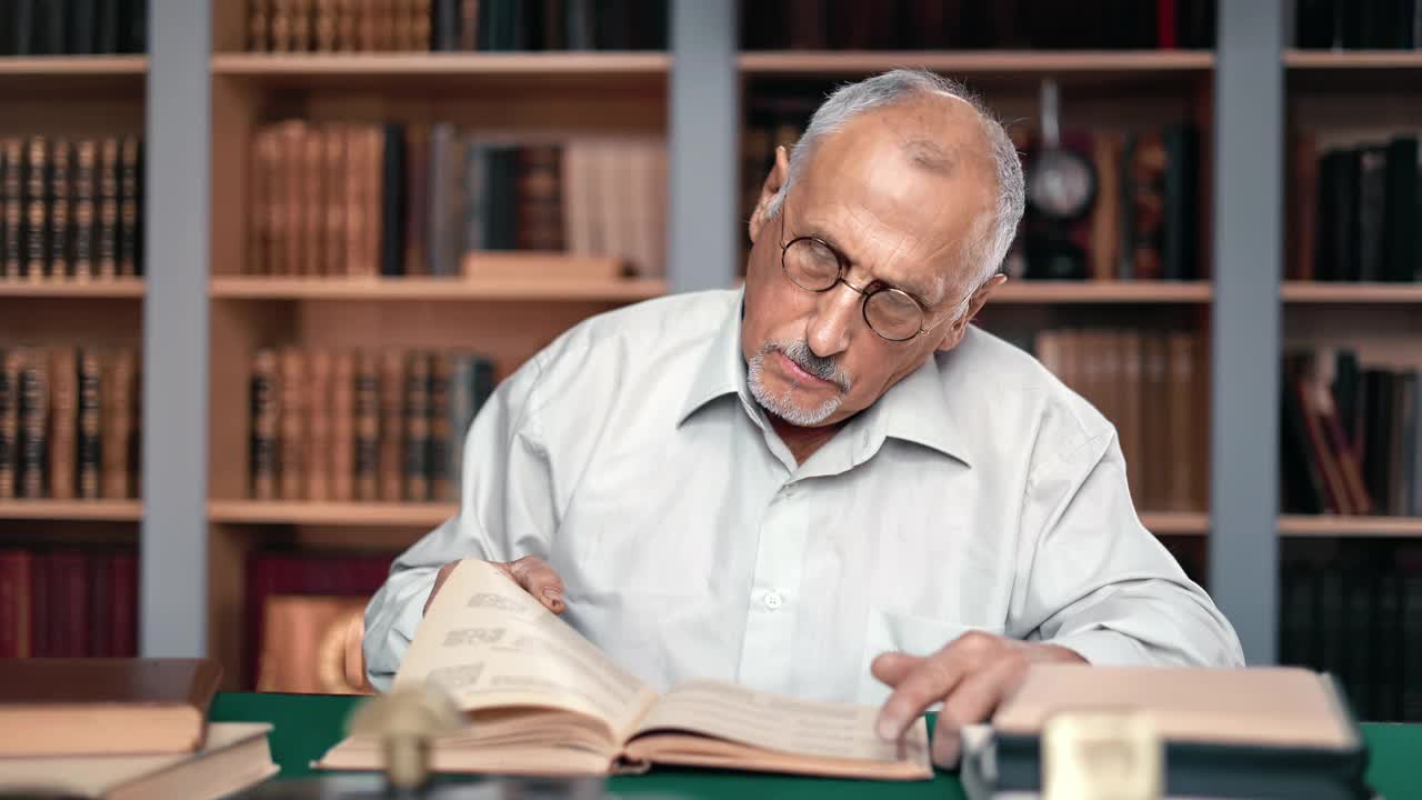 沉思的70年代老人科学家教授在公立大学图书馆阅读旧纸书视频素材