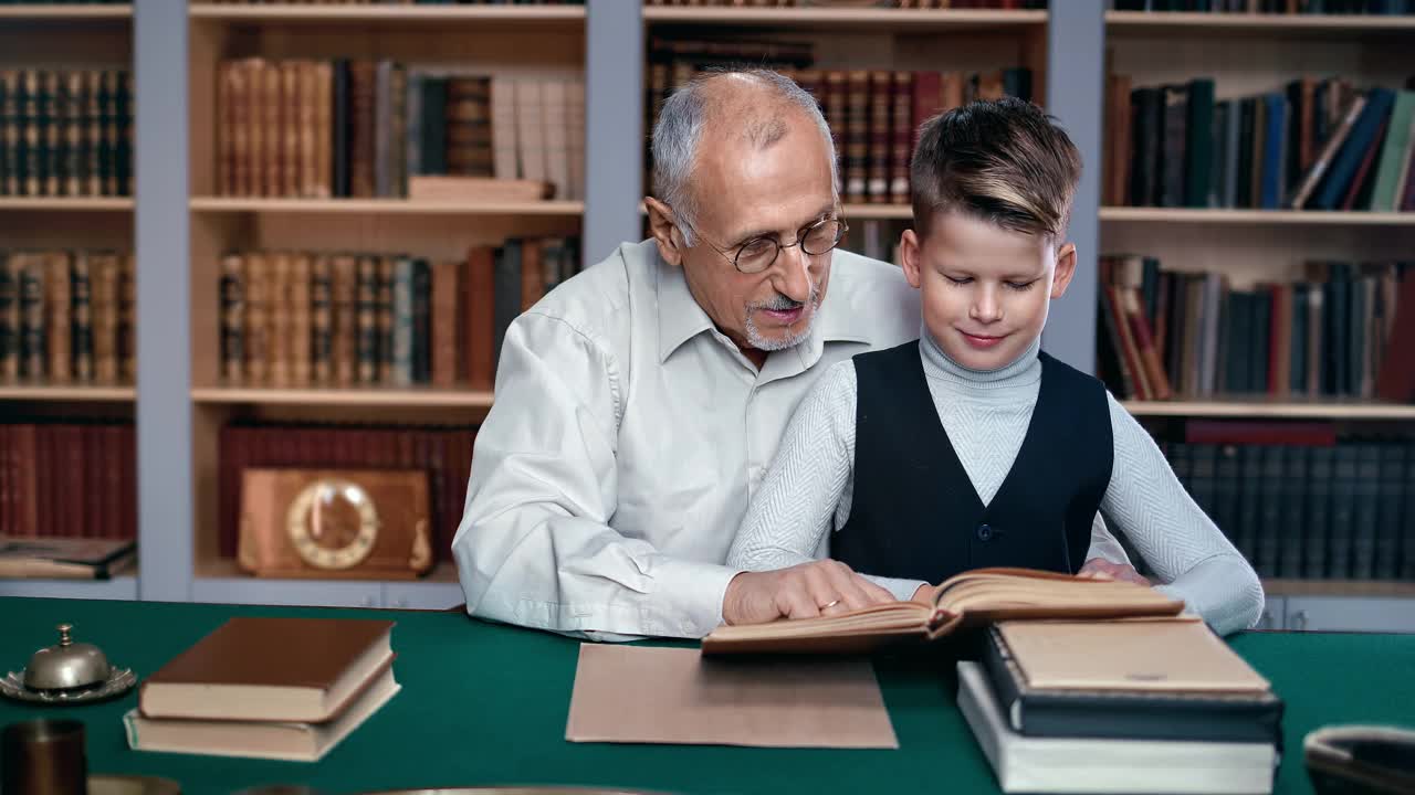 70年代的爷爷和小男孩在复古的公共图书馆阅读教科书解释谈话感觉爱视频下载
