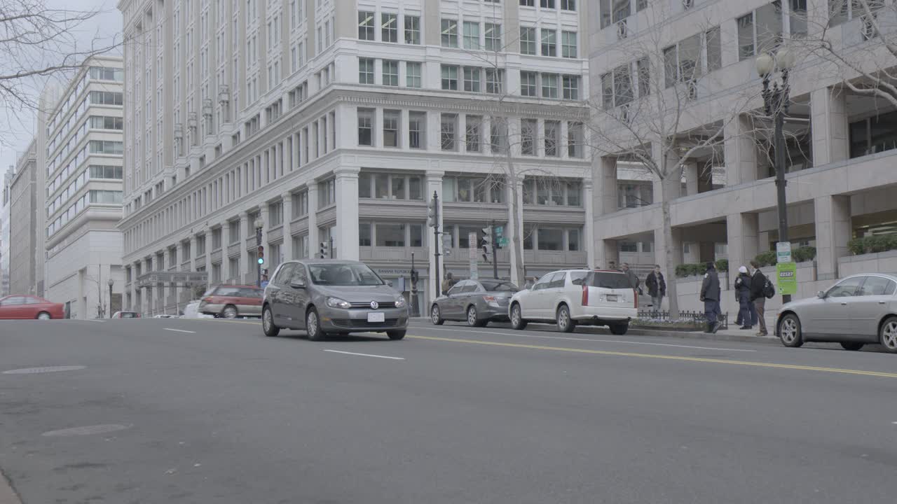 当一辆黑色suv在城市街道上驶过时，车内的警灯正在闪烁。可能是特勤局或者联邦调查局。政府大楼可见。视频素材