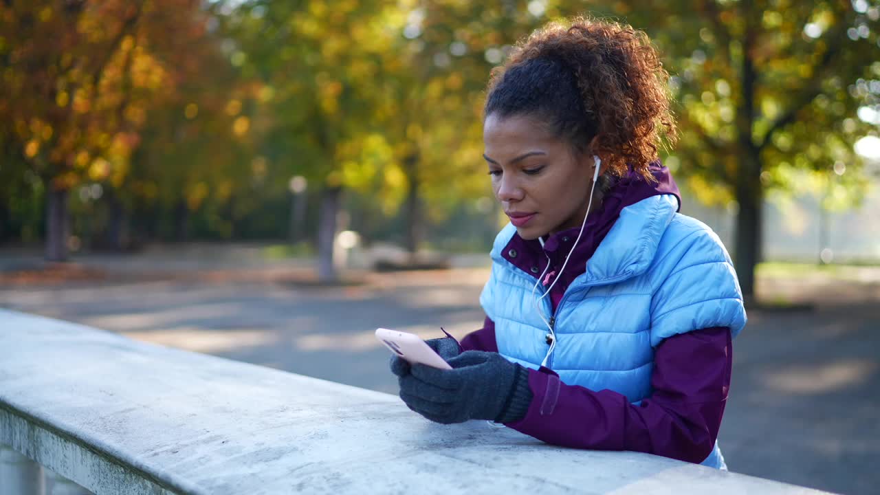 女运动员在秋天的公园里发短信视频素材