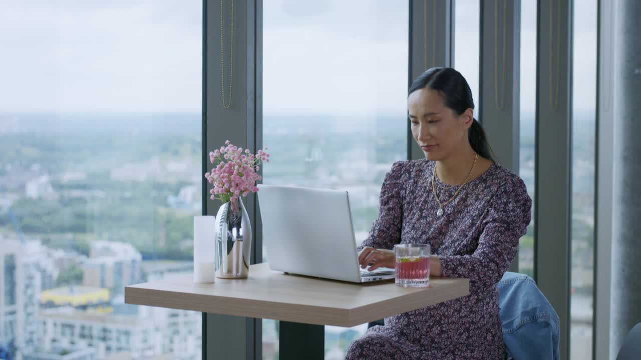 中国女商人在屋顶酒吧用笔记本电脑打字视频素材