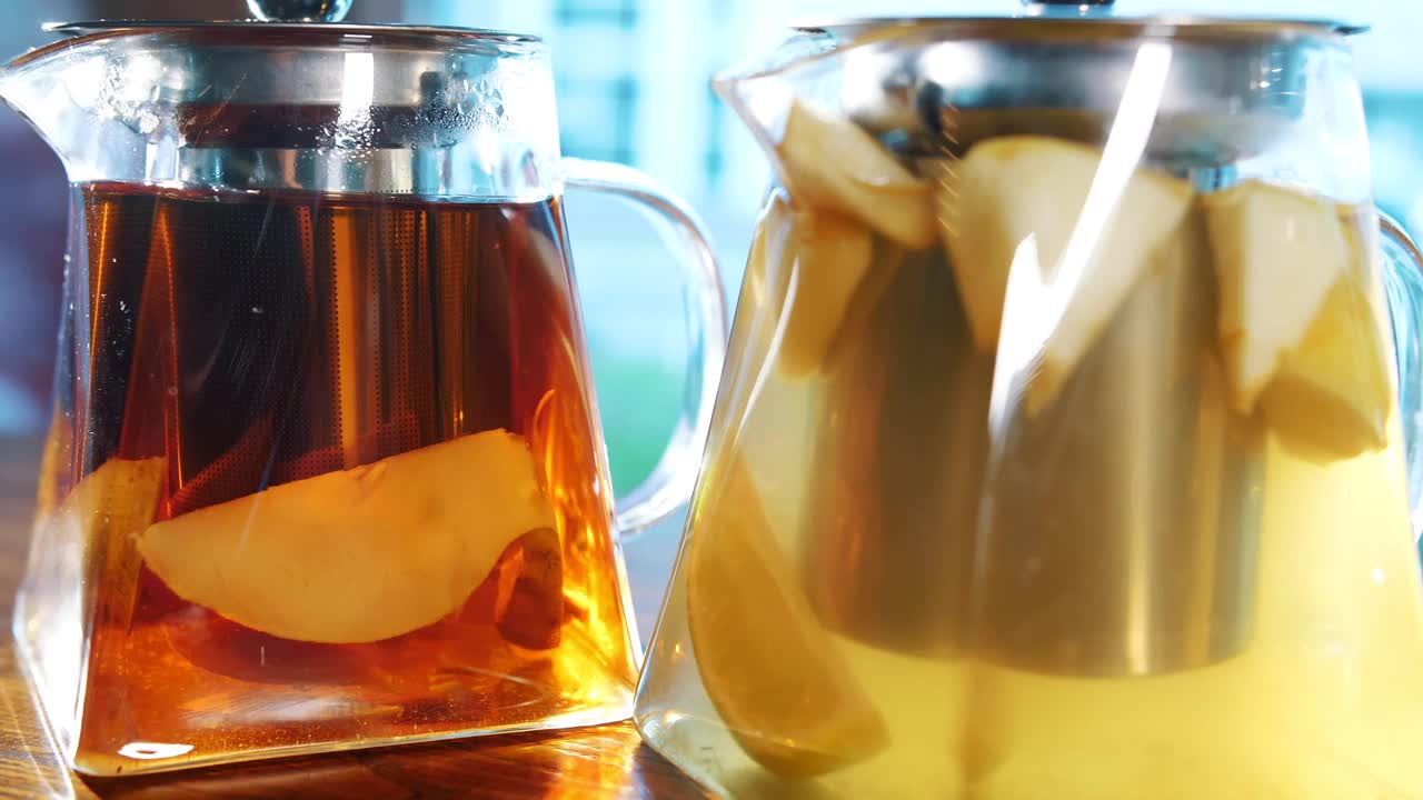 茶壶里的水果茶。花草茶。茶饮料。特写镜头。三个玻璃茶壶，里面有不同的水果和草药，五颜六色的自制茶视频素材