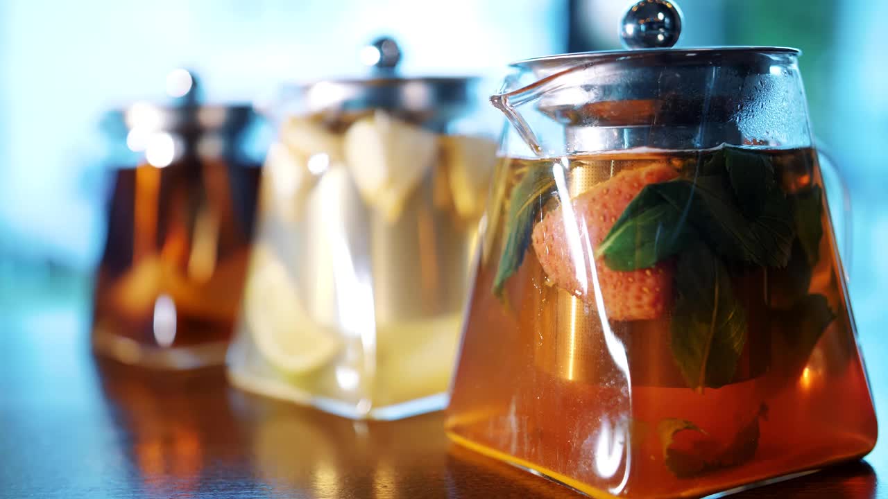 茶壶里的水果茶。花草茶。茶饮料。特写镜头。三个玻璃茶壶，里面有不同的水果和草药，五颜六色的自制茶视频素材