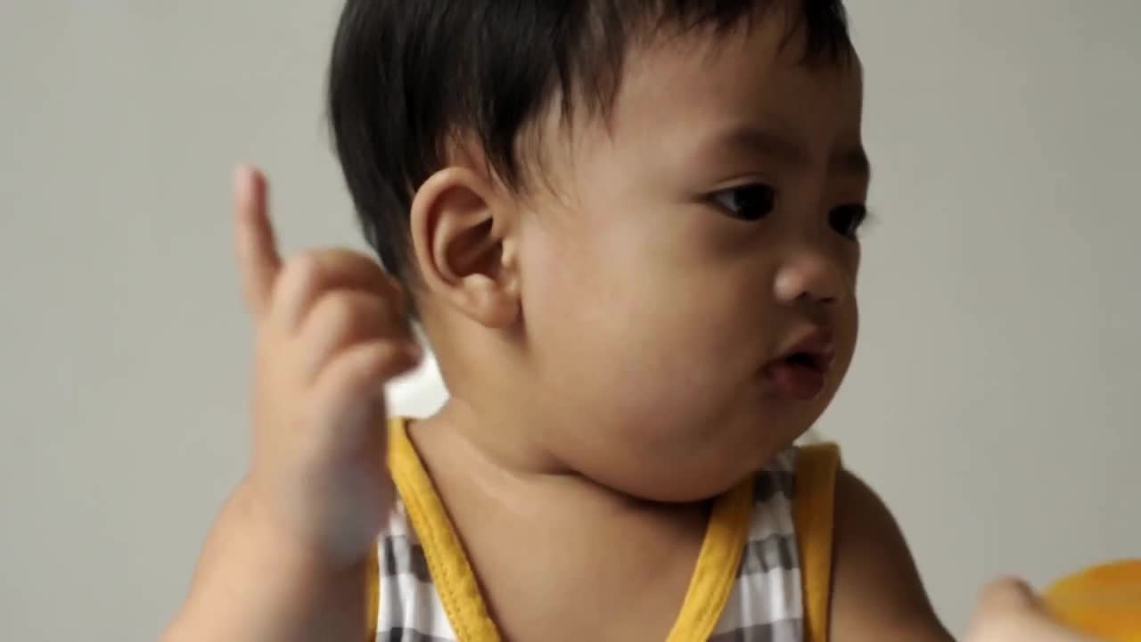 一个东南亚男婴正在吃一片成熟的芒果视频下载