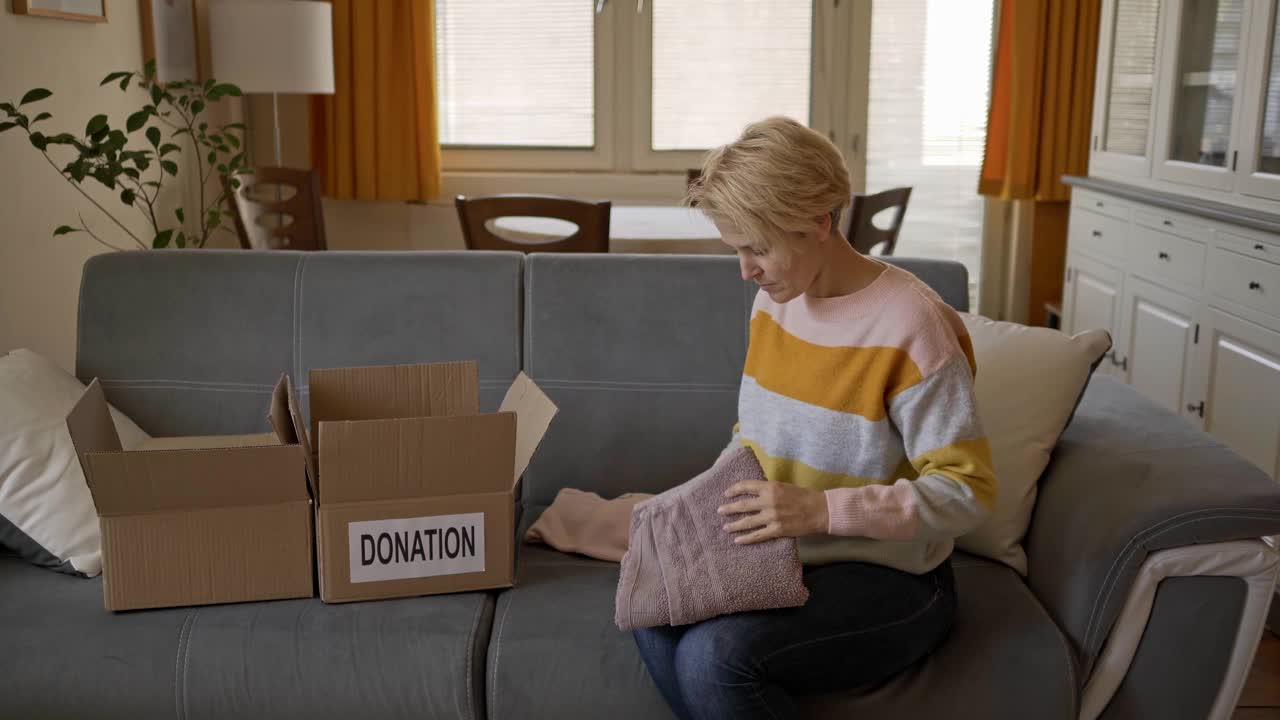 把毛巾叠在膝盖上，然后装进盒子里，这是一笔慷慨的慈善捐赠视频素材