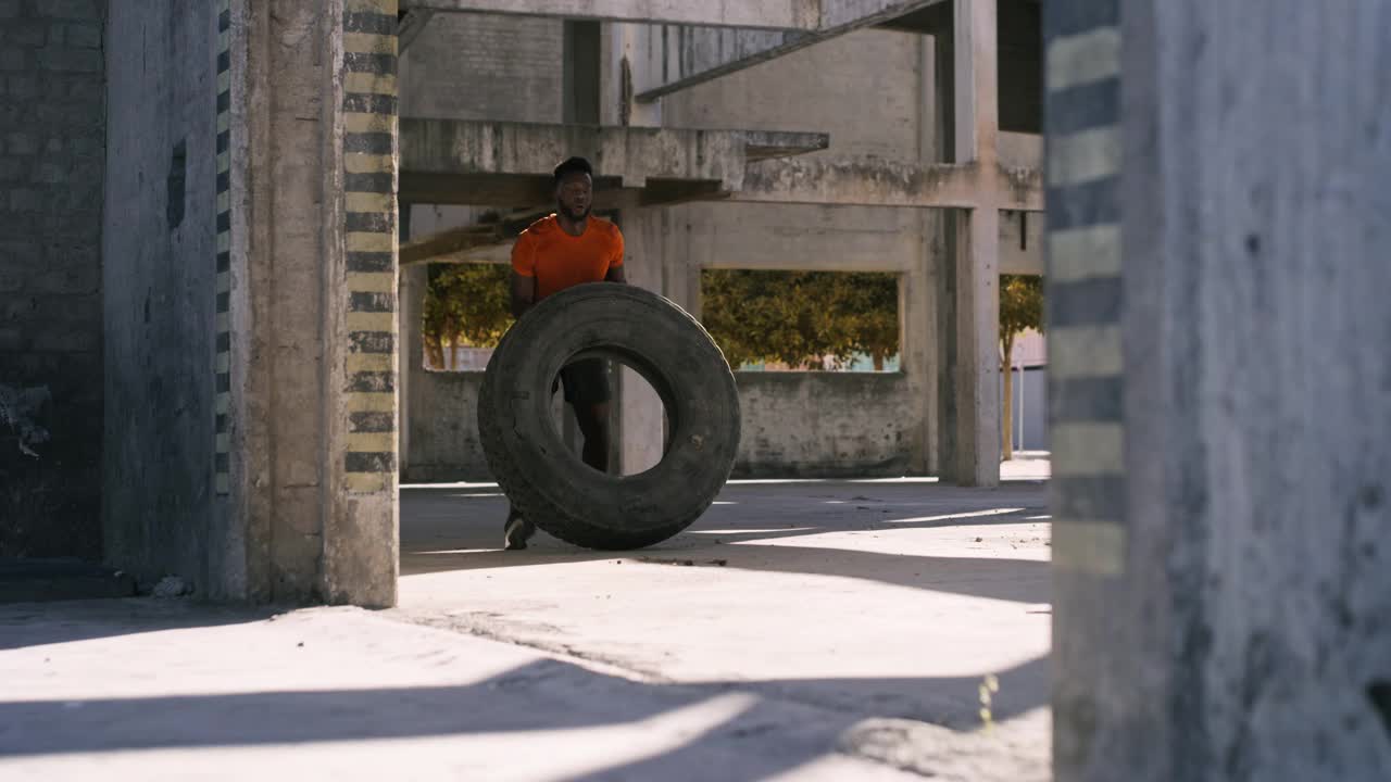 一个年轻人在城市背景下锻炼时举起轮胎的4k视频片段视频素材