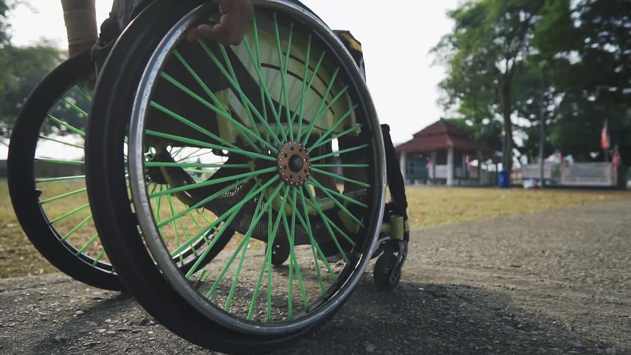 低角度残疾的亚洲印度人，坐在轮椅上，在公园进行晨间例行运动训练视频下载