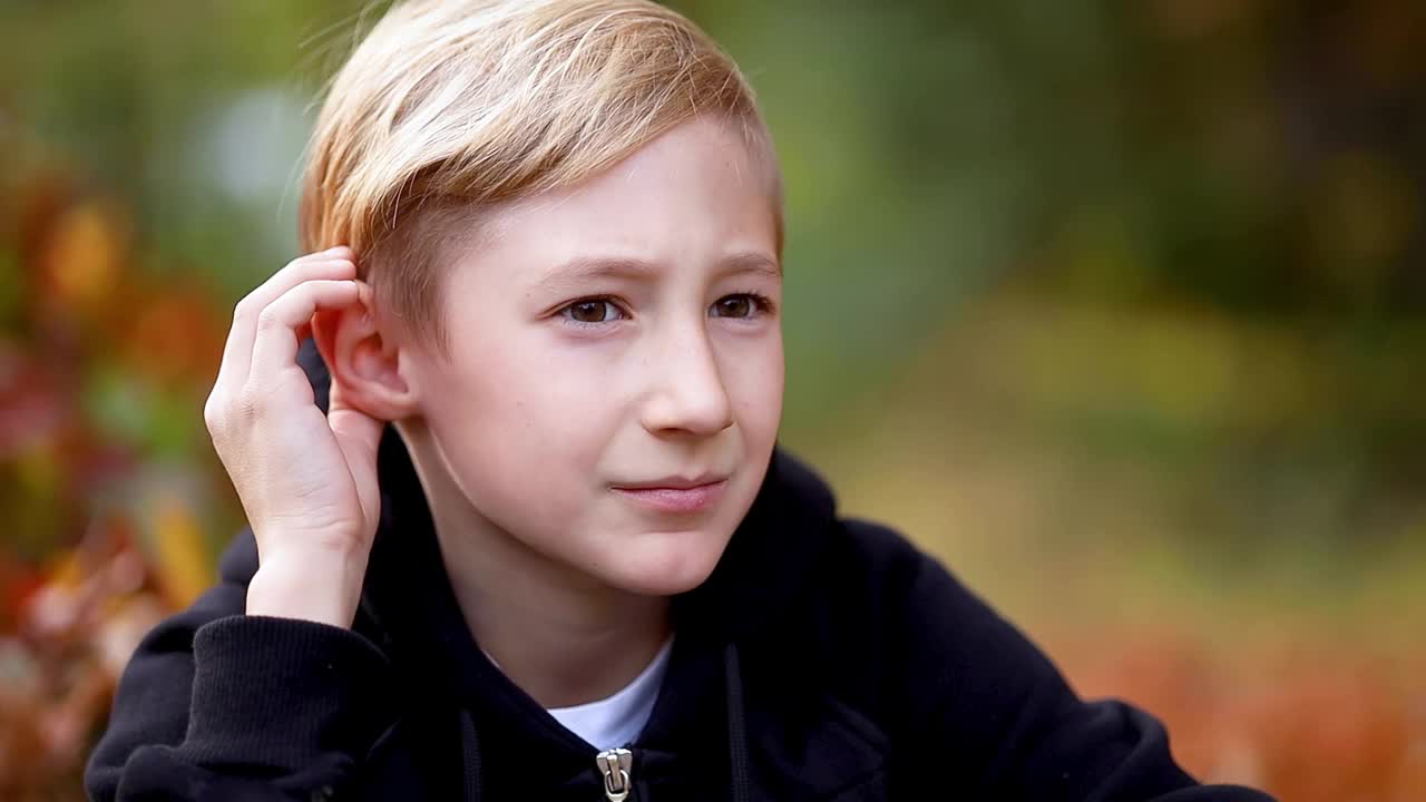 一个男孩在秋天的公园里挠着后脑勺视频下载