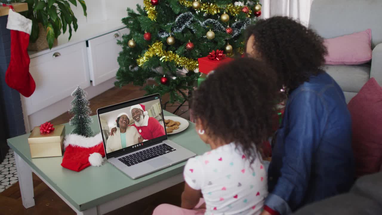 非裔美国母亲和女儿在圣诞节期间在家里用笔记本电脑进行视频通话视频下载