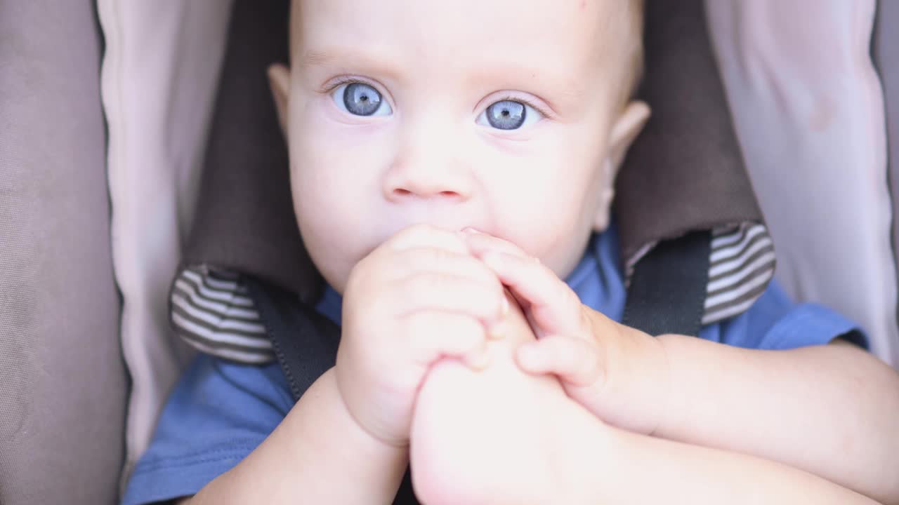 特写肖像白种人婴儿婴儿蓝眼睛坐在棕色的儿童马车视频素材