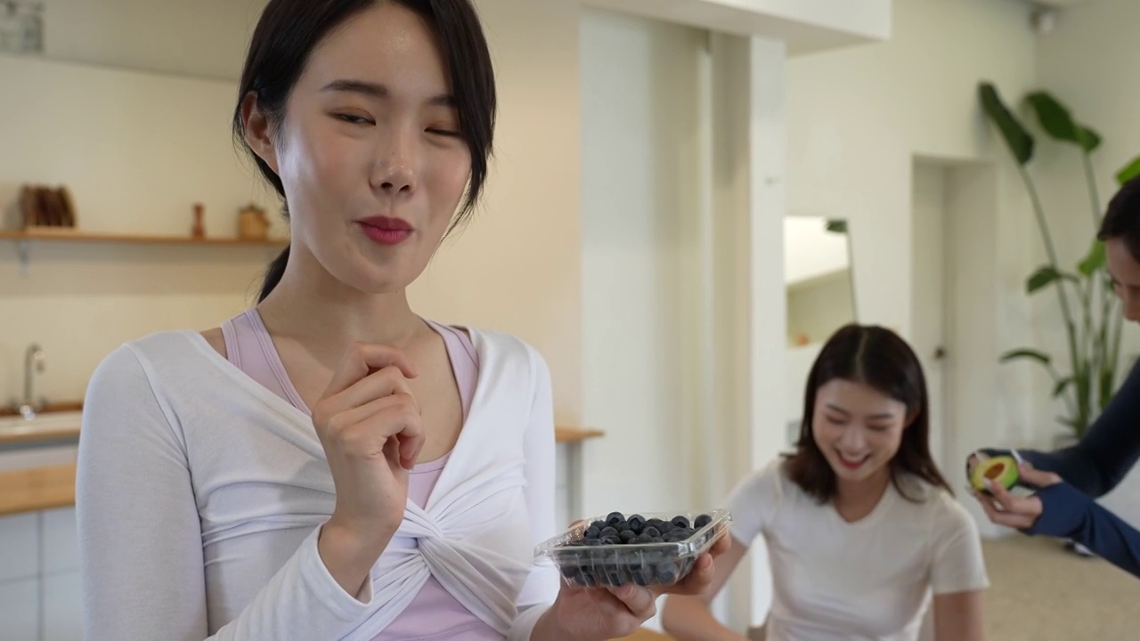 年轻女子，面带微笑，边看镜头边吃蓝莓/韩国视频下载