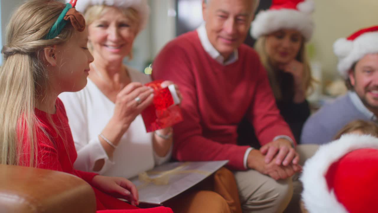 几代人的家庭在家里的圣诞树旁交换和打开礼物视频素材