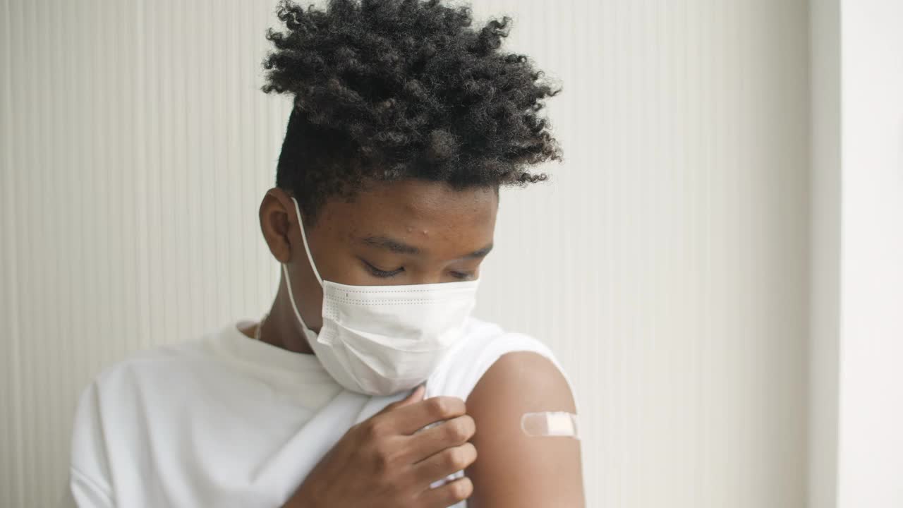 一名非洲裔美国青少年在接种疫苗后竖起大拇指，并展示手臂上的绷带视频素材