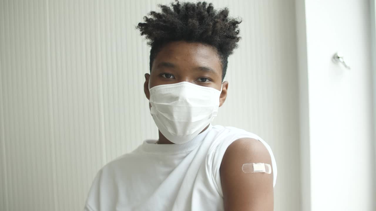 一名非洲裔美国青少年在接种疫苗后竖起大拇指，并展示手臂上的绷带视频素材