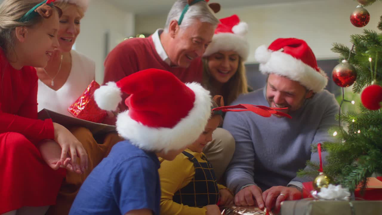 几代人的家庭在家里的圣诞树旁交换和打开礼物视频素材