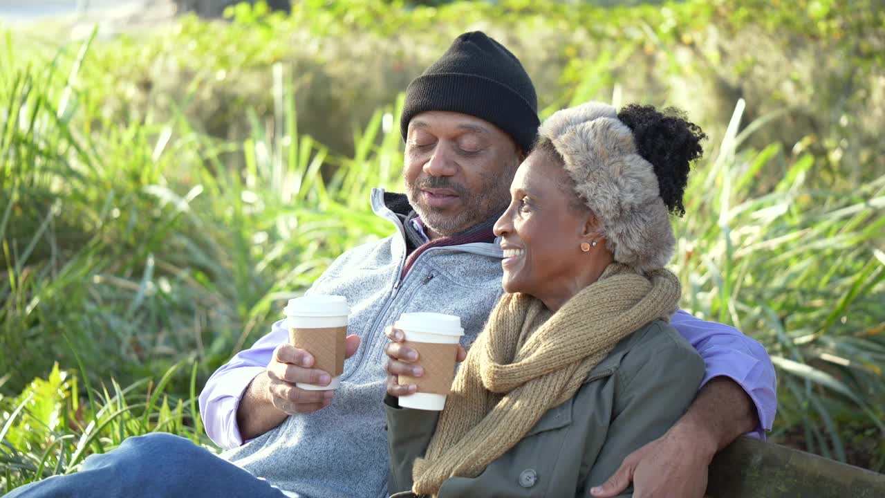 非裔美国夫妇在公园长椅上休息，喝咖啡视频素材