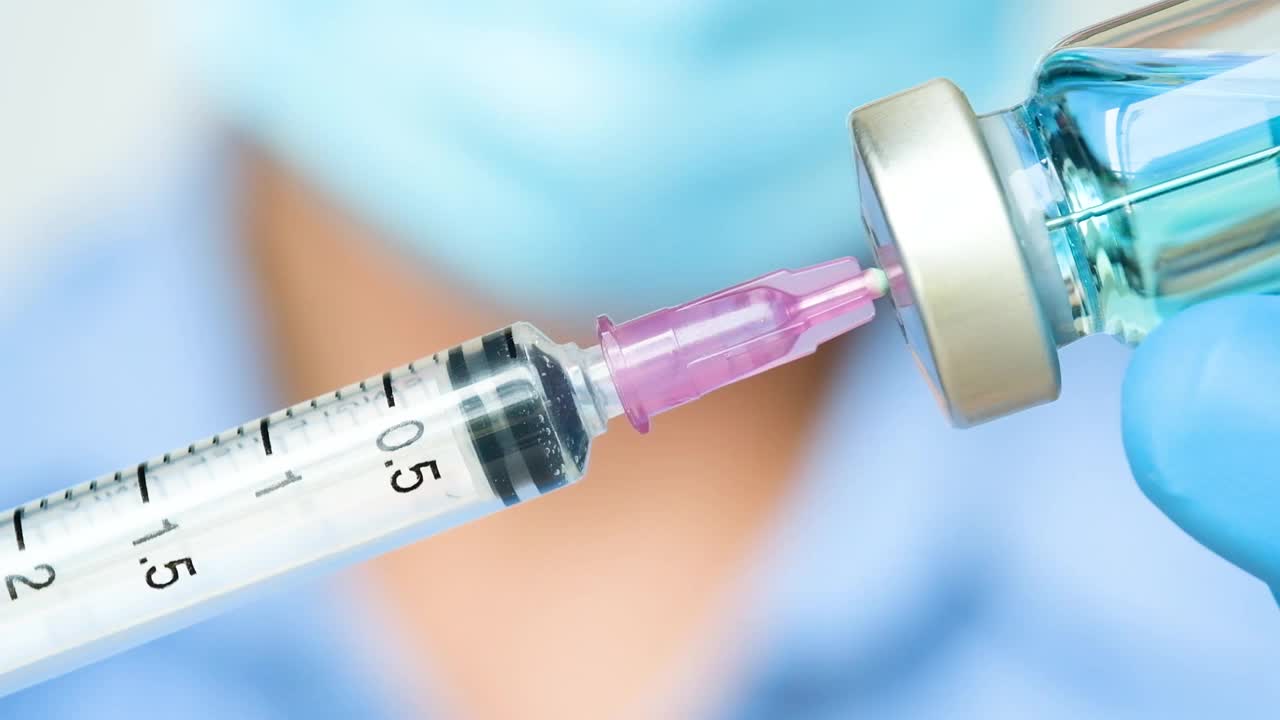 在医院里，医生的手拿着一个注射器和一个蓝色的疫苗瓶。健康和医学概念。视频素材