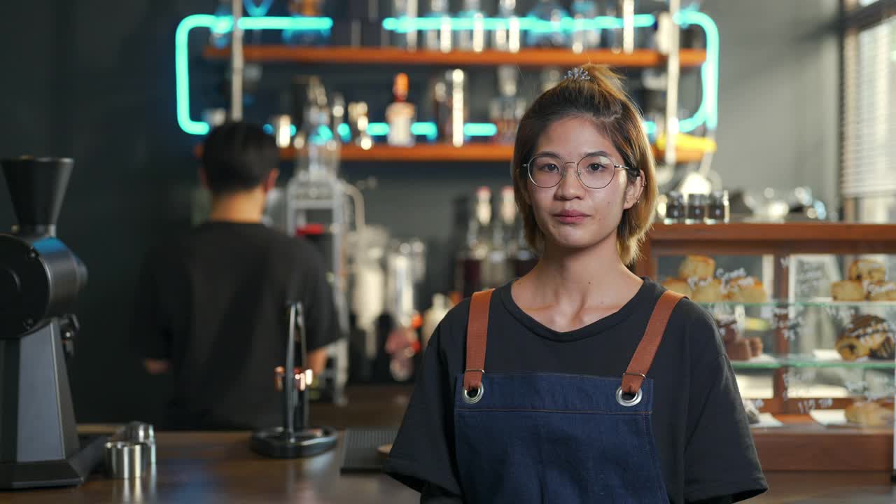 4K亚洲女咖啡厅老板的肖像，双手交叉站在吧台前视频素材