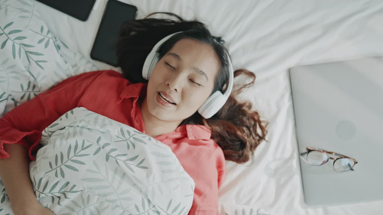 女人在家里的床上享受她最喜欢的音乐视频素材