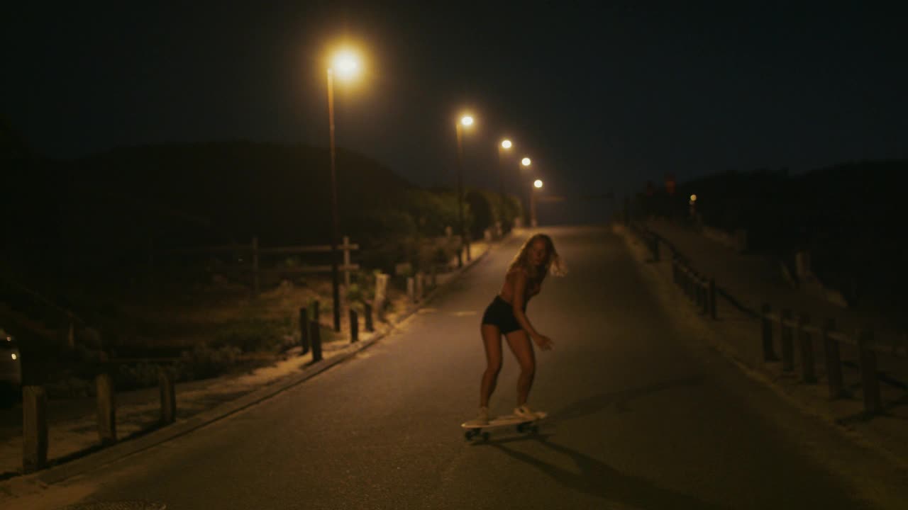 年轻女子滑着滑板下山视频下载