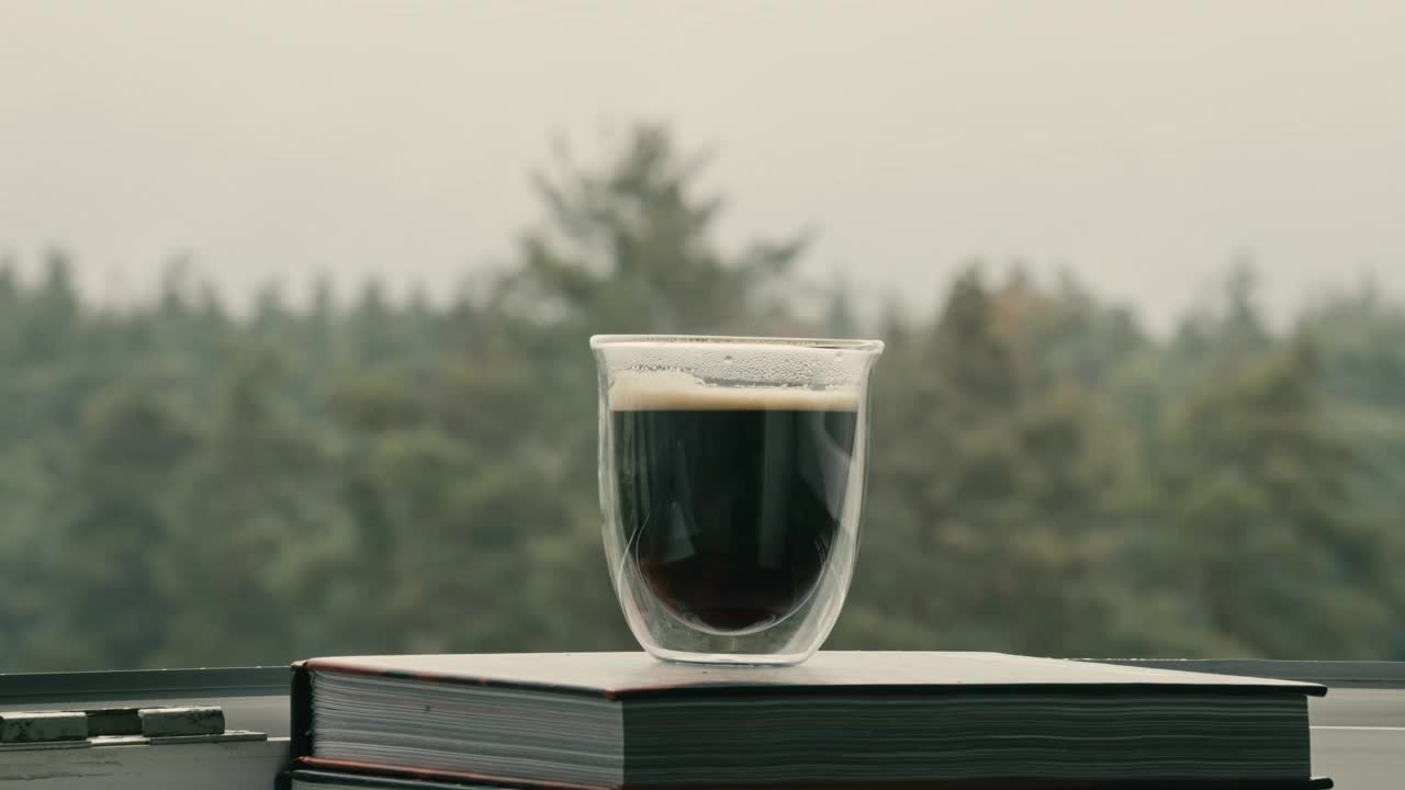 一杯刚煮好的咖啡在窗台上等，欣赏美丽的森林景色视频下载
