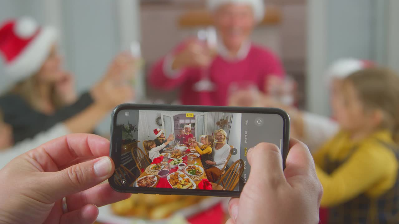 一名男子用手机拍摄几代人在圣诞节吃饭的POV照片视频下载