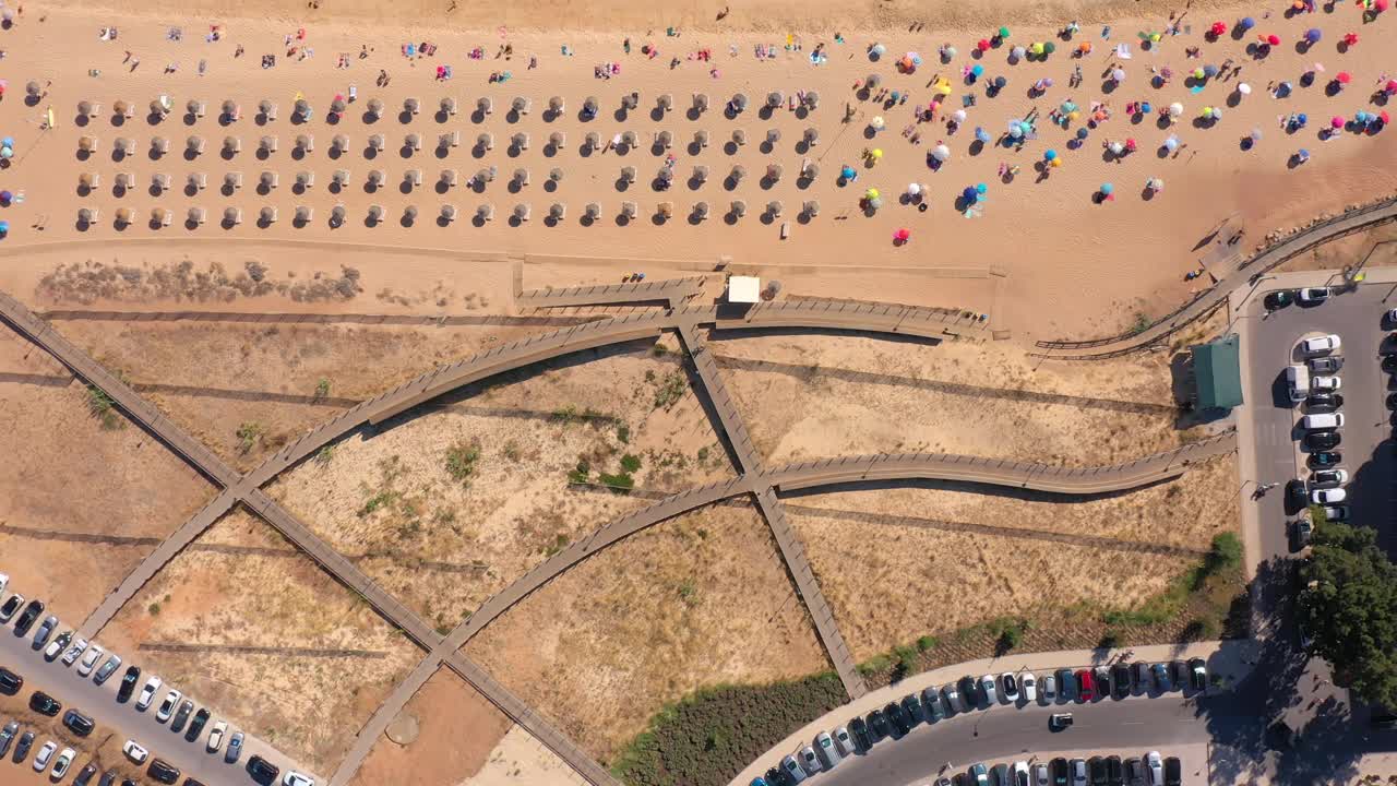 天线。无人机在葡萄牙小镇夸特伊拉的海滩和木路上空飞行，游客们躺在阳光躺椅上。葡萄牙阿尔加维。俯视图视频素材