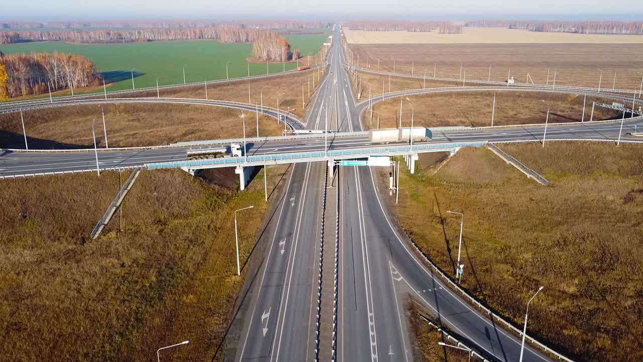 无人机视野的高速公路多层次路口与移动的汽车。电影无人机拍摄飞行在乡村道路与秋天的树在日落视频素材
