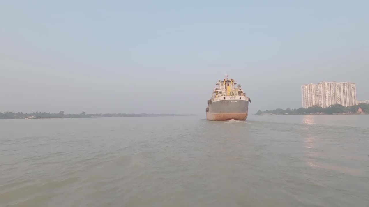 一艘集装箱货船从希迪尔普尔港启航后经过恒河。在日落的背景下，在晴朗的天空下乘船旅行的镜头。印度加尔各答亚洲视频素材
