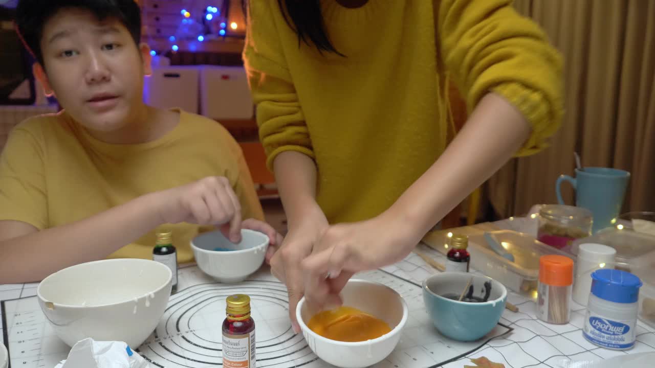 晚上，亚洲的孩子们在家里一起用糖混合颜色来装饰万圣节饼干。视频下载