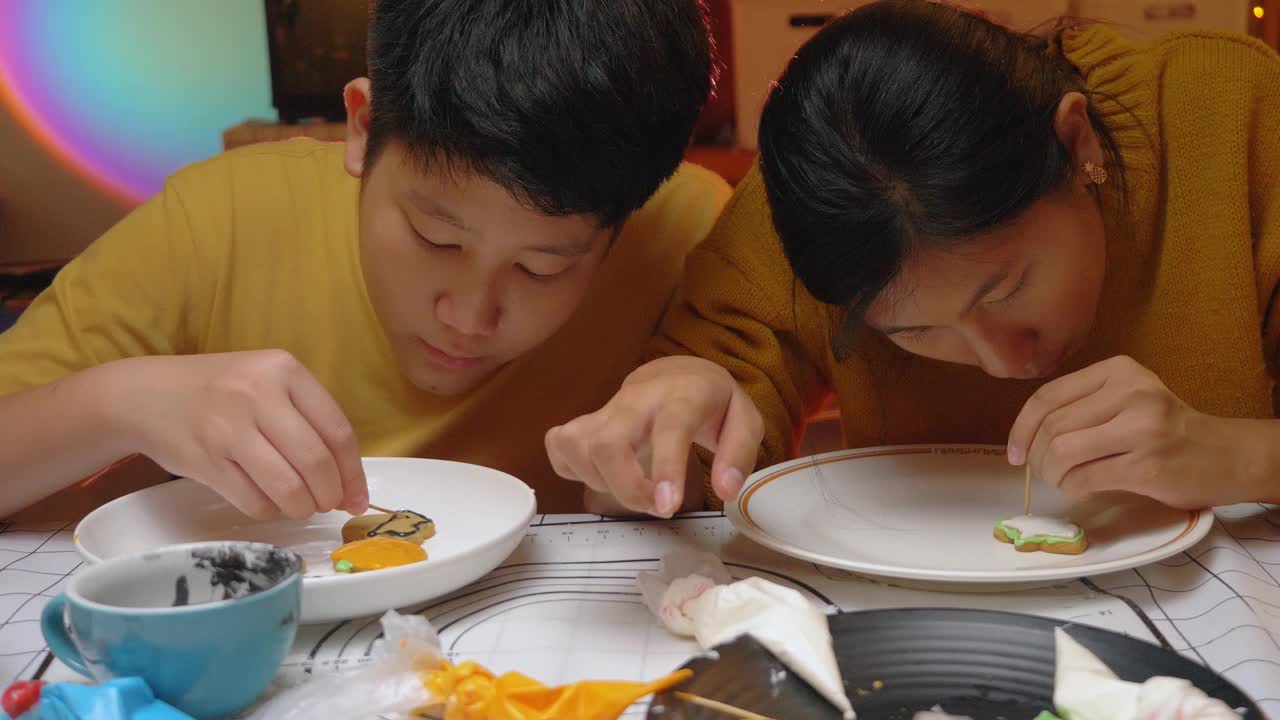 亚洲孩子晚上在家里一起装饰饼干，万圣节的生活理念。视频下载
