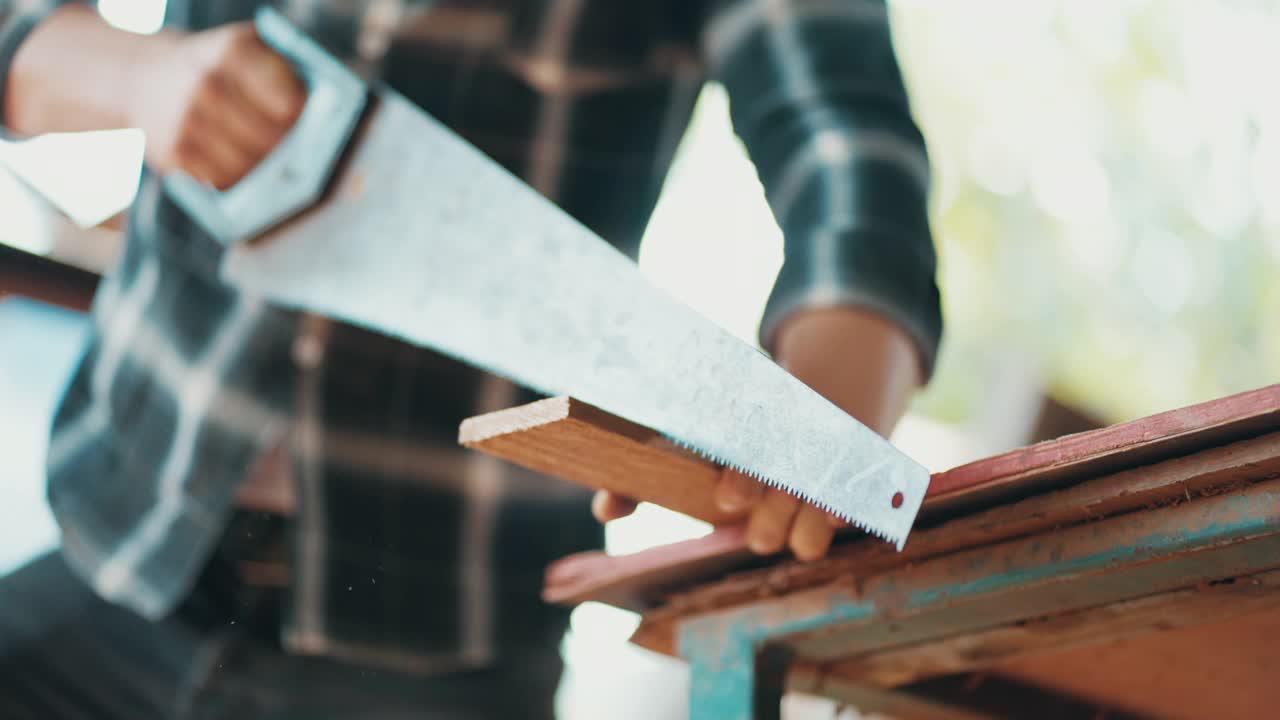 慢动作:木匠用手锯切割木材视频下载
