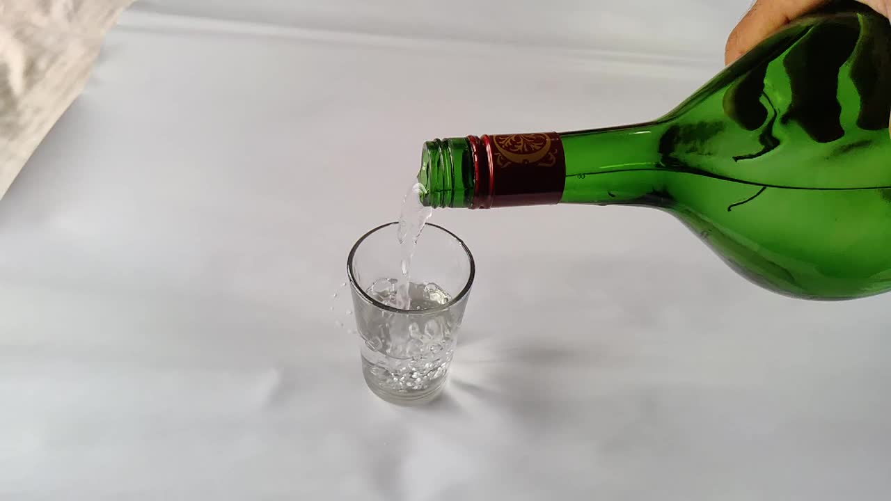 将饮料从瓶子倒向玻璃杯的慢动作特写镜头视频下载