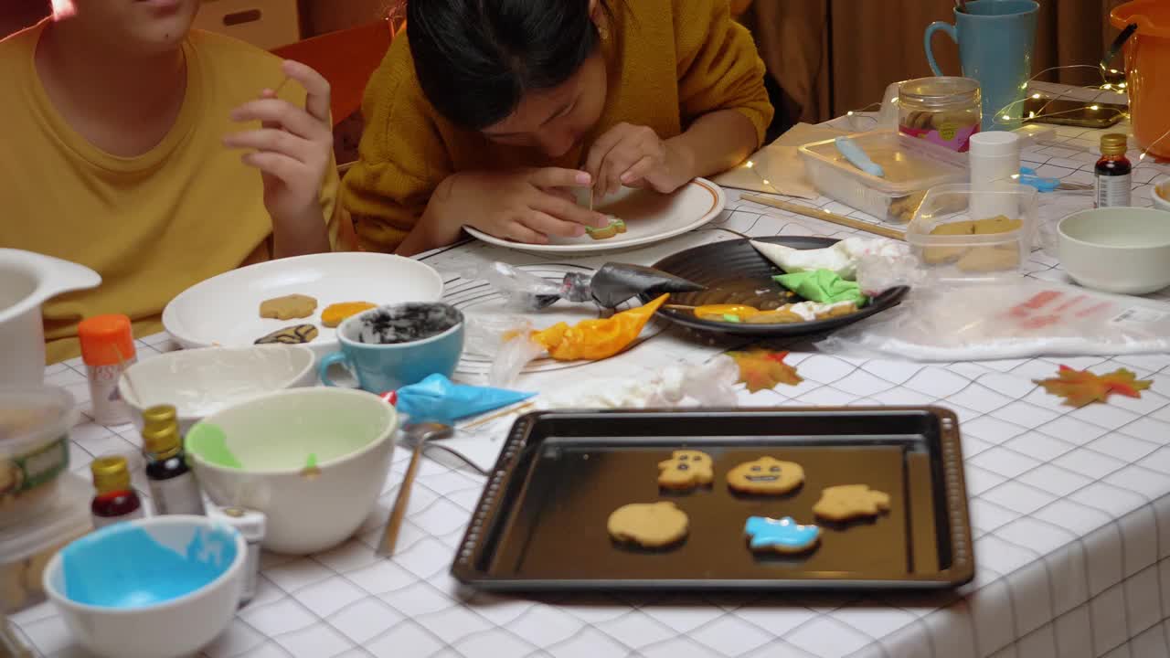 亚洲孩子晚上在家里一起装饰饼干，万圣节的生活理念。视频下载