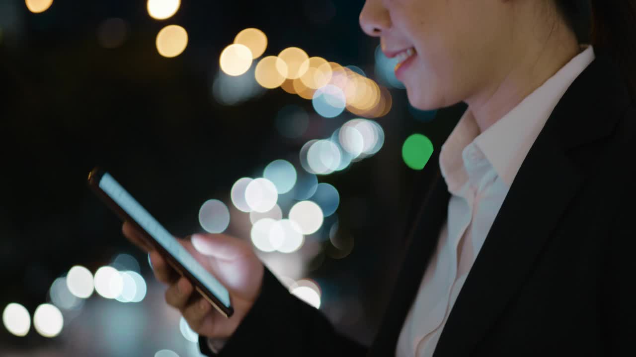 女商人在晚上走在城市里使用智能手机视频素材