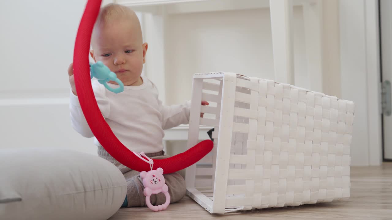 宝宝坐在地板上看着一个白色的玩具盒玩着玩具，可爱的小男孩正在探索新的世界。视频下载