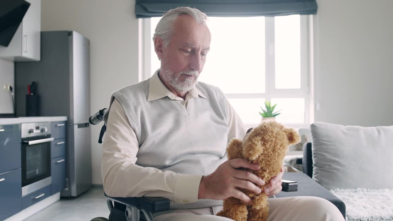 坐在轮椅上的老人抱着泰迪熊玩具，感到孤独，想念家人视频素材
