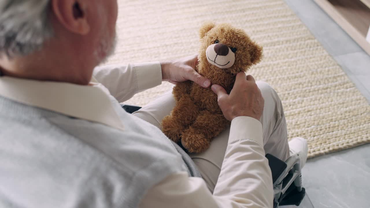 残疾老人抱着孙子的玩具，在敬老院感到孤独视频素材