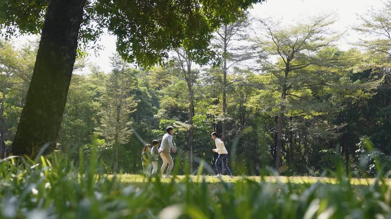 一个亚洲家庭和两个孩子在城市公园户外玩耍视频素材