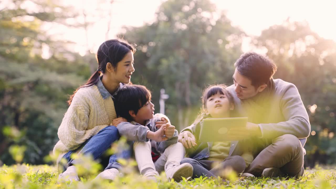 年轻的亚洲家庭在公园草地上放松视频素材