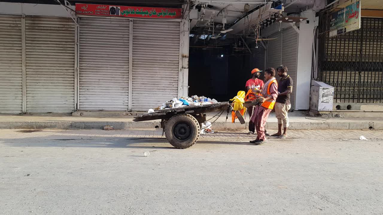 垃圾收集工人在路边用老式的木制推车收集垃圾。视频素材