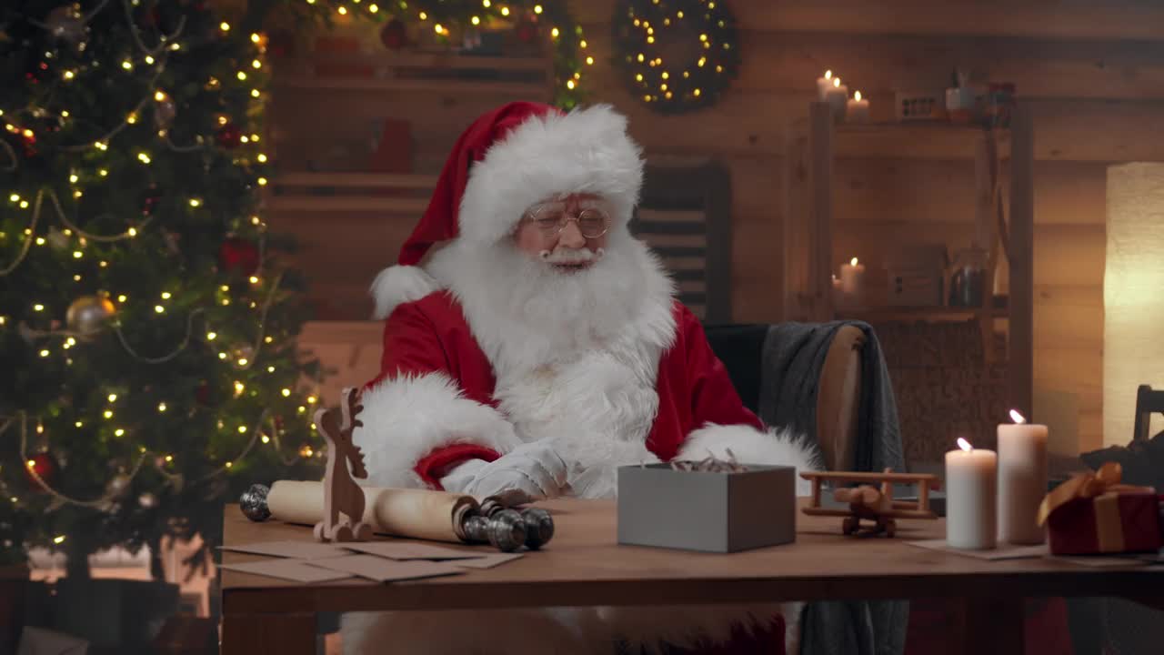 圣诞老人正微笑着把礼物装进小盒子里视频素材