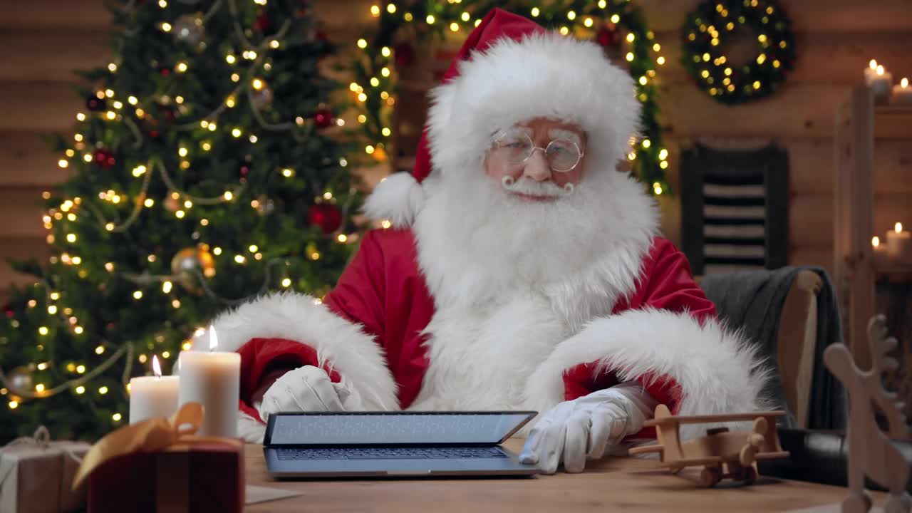 圣诞老人打开一台空屏幕的笔记本电脑，在摄像头里显示了他竖起的大拇指视频素材